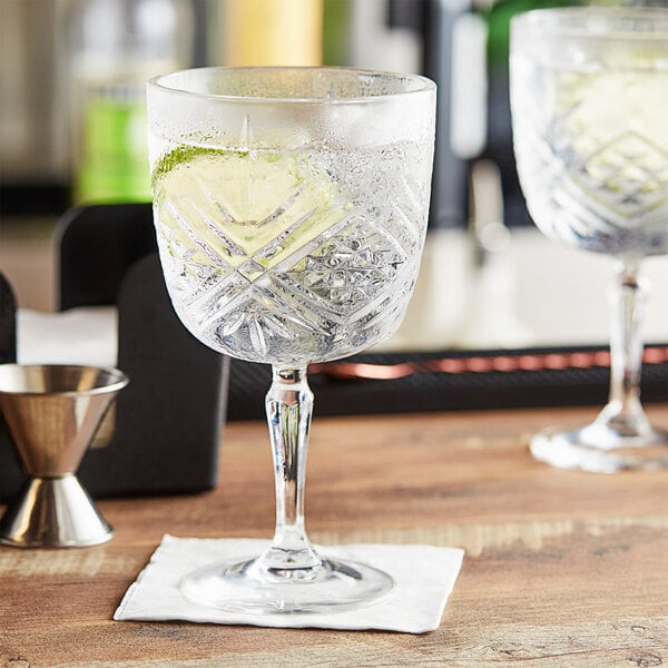 Two Arcoroc gin and tonic glasses on a bar counter with a lime wedge in one.