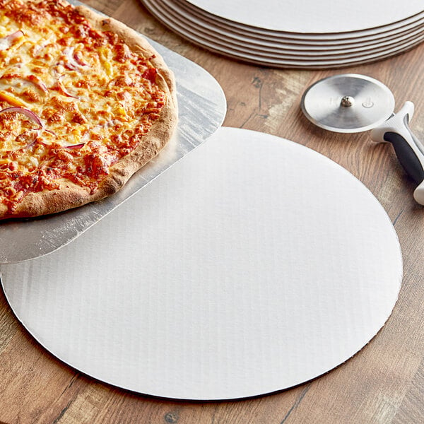 A pizza on a white corrugated tray next to a pizza cutter.