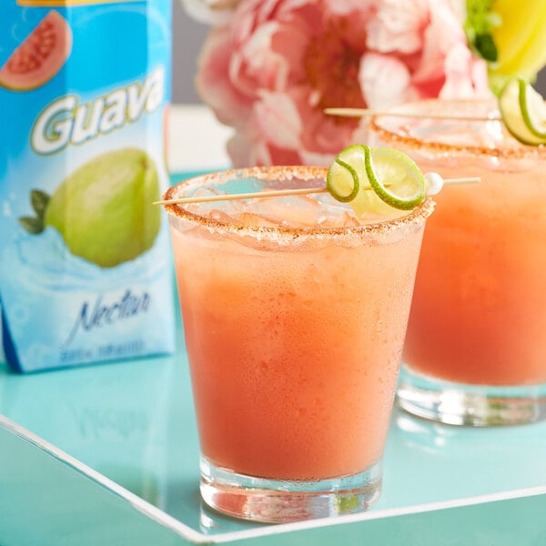 Two glasses of guava nectar with a lime wedge.