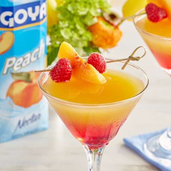 A glass of Goya Peach Nectar with fruit garnish on the rim.