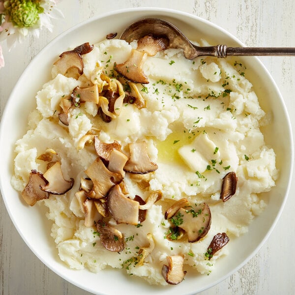 A bowl of Idahoan mashed potatoes with mushrooms and a spoon.