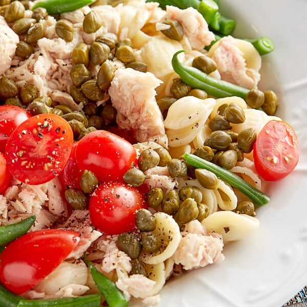 A plate of pasta with tomatoes, green beans, and Goya Spanish capers.