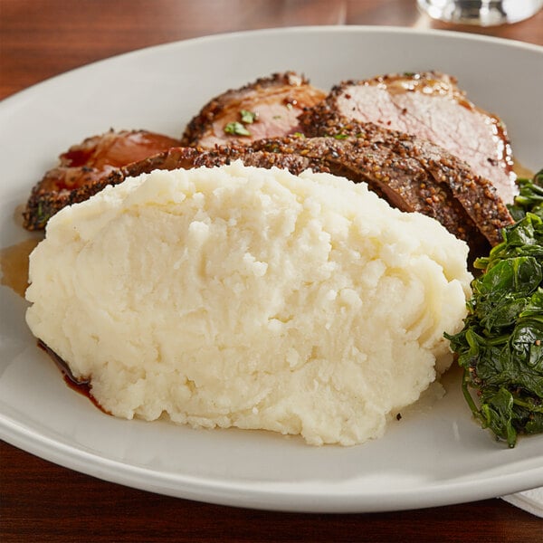 A plate of mashed potatoes and greens on a table.