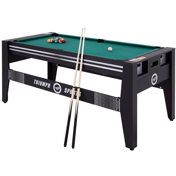 A Triumph 4-in-1 game table with cue sticks on a pool table.