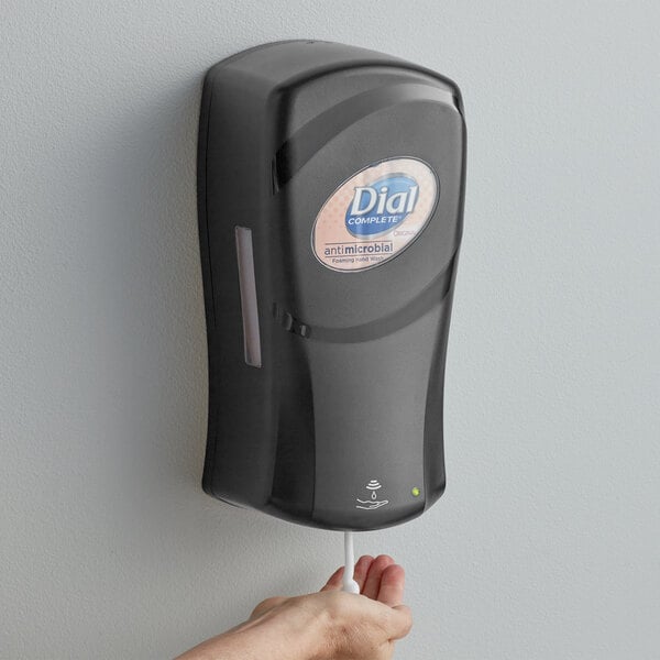 A hand using a Dial FIT Universal touch-free hand sanitizer dispenser.
