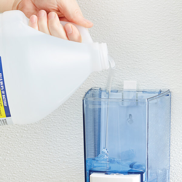 A person pouring Dial Sensitive Skin liquid hand soap into a jug.