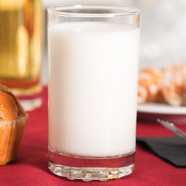 A Libbey customizable beverage glass filled with milk on a table with muffins.
