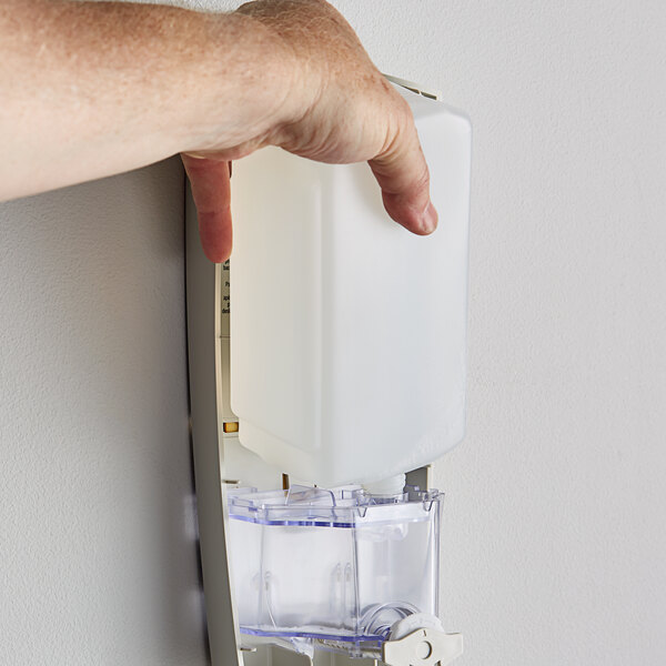 A hand pushing a Dial Sensitive Skin hand soap refill into a dispenser.
