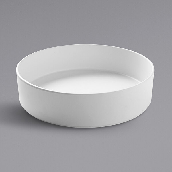 A white Cal-Mil stackable melamine bowl on a gray surface.