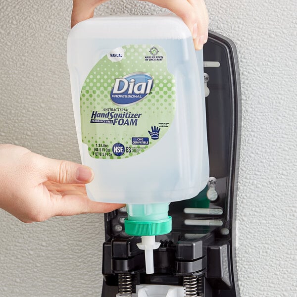 A hand holding a Dial FIT Universal foam hand sanitizer refill container.