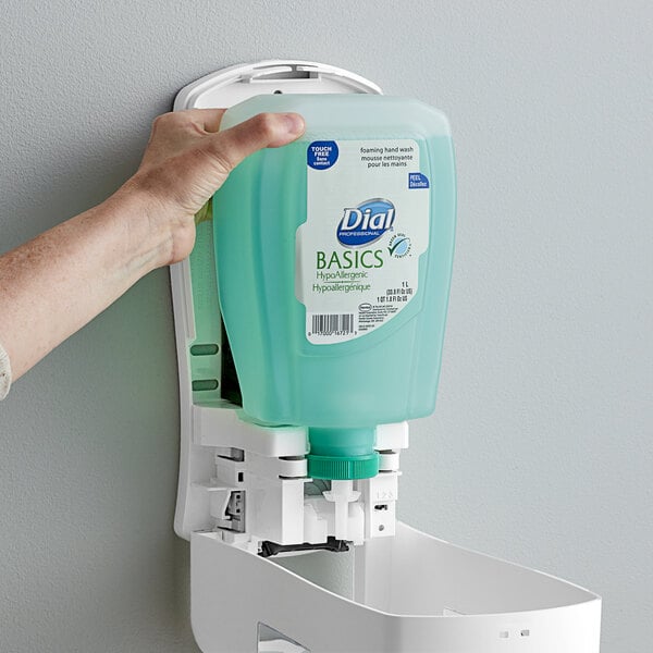A hand holding a green Dial foaming hand soap refill container.