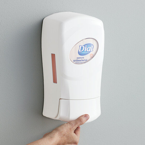 A person's hand using a white Dial hand soap dispenser.