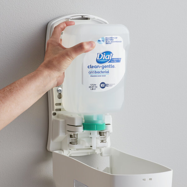 A hand reaching out to a Dial Clean and Gentle foaming hand wash refill bottle.