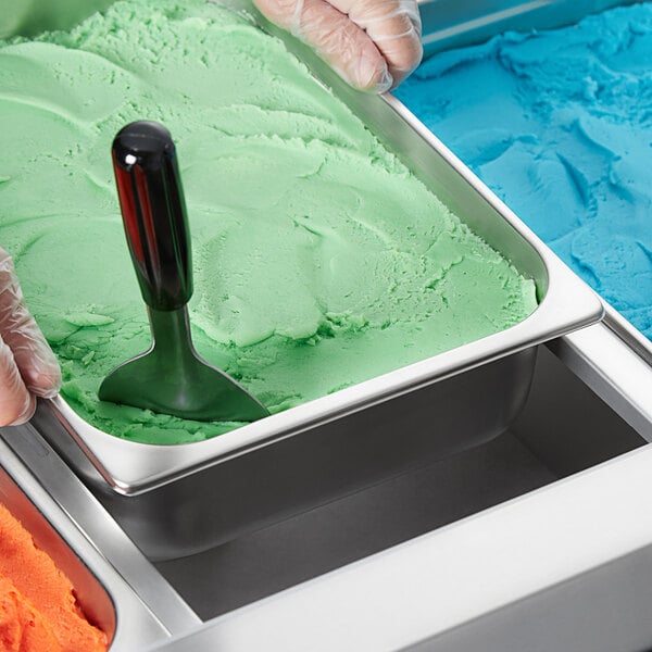 A person using a Choice stainless steel gelato pan to scoop green ice cream.