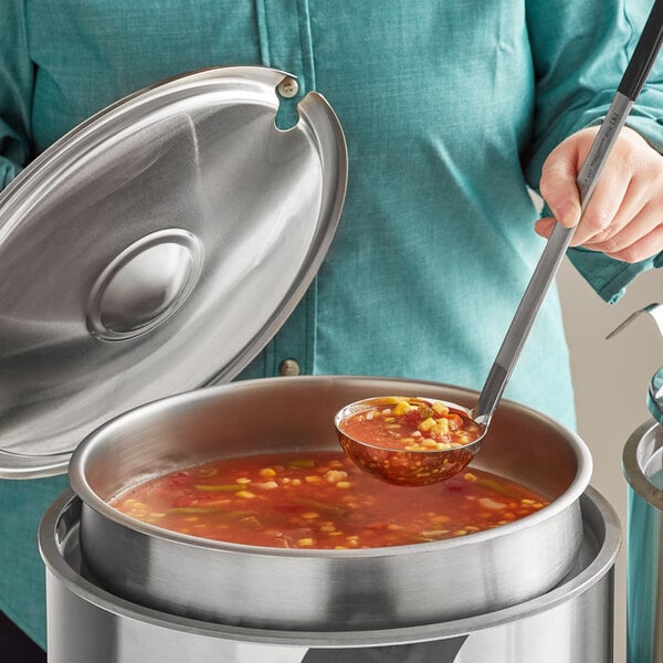 A woman using a Jacob's Pride ladle to serve soup from a Vollrath stainless steel inset on a table