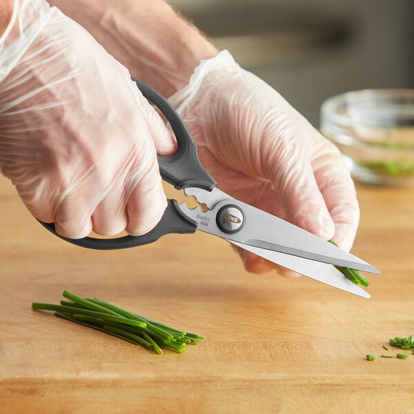 A person in gloves cutting chives with OXO kitchen shears.