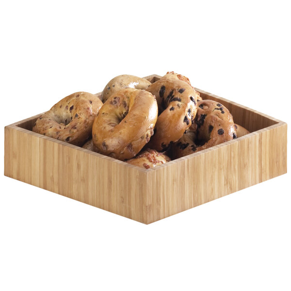 A Cal-Mil bamboo wooden tray with bagels in it on a table.
