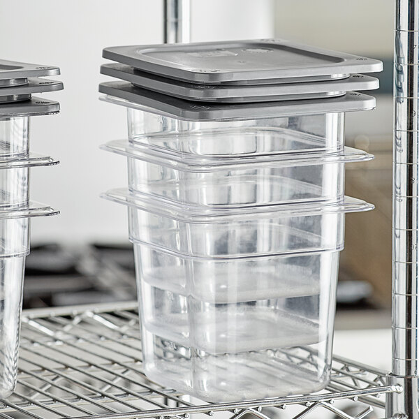 A metal rack holding three Vigor clear plastic food pans with secure sealing covers.