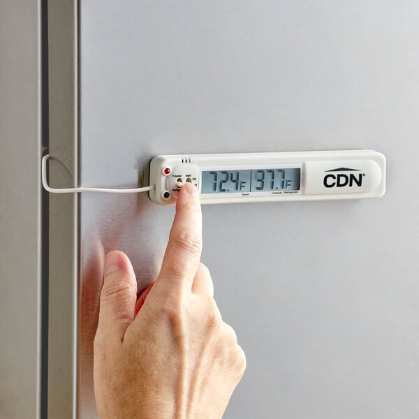 A person using a CDN digital refrigerator thermometer to check the temperature of a refrigerator.