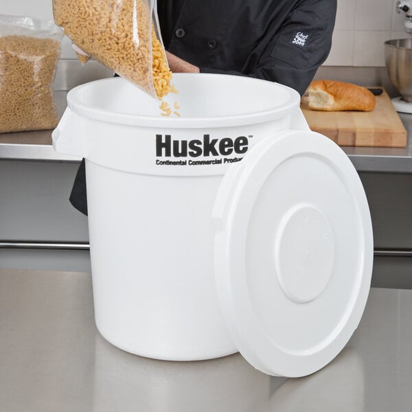 A man pouring grains into a white container with a flat top lid.