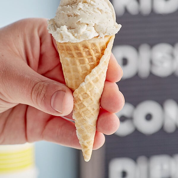 A hand holding a Joy sugar cone filled with vanilla ice cream.