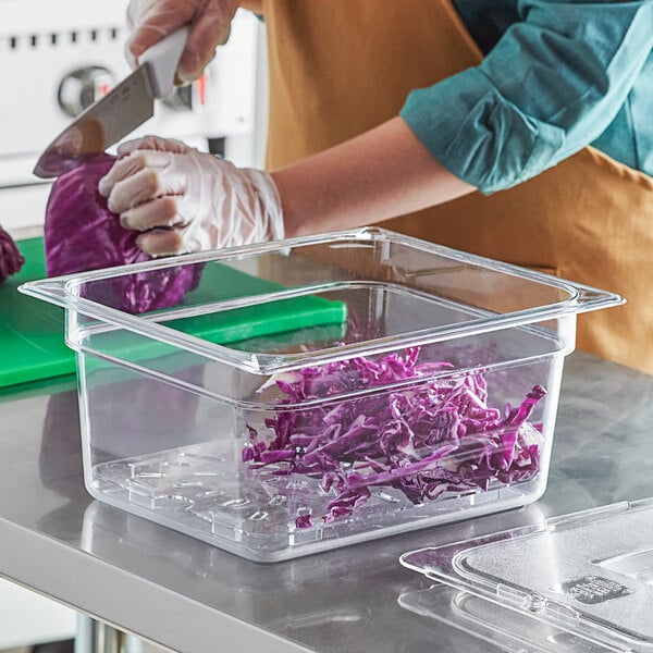 A woman in gloves cutting purple cabbage in a Vigor plastic food pan.