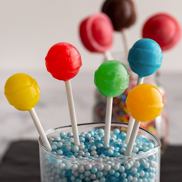 A glass vase filled with colorful lollipops and candy on Paper Lollipop sticks.