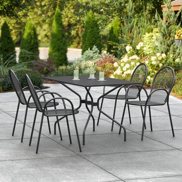 A Lancaster Table & Seating Harbor black rectangular outdoor table with chairs on a patio.
