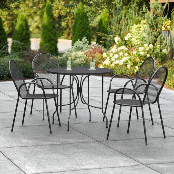 A Lancaster Table & Seating Harbor black outdoor table with black ornate chairs.