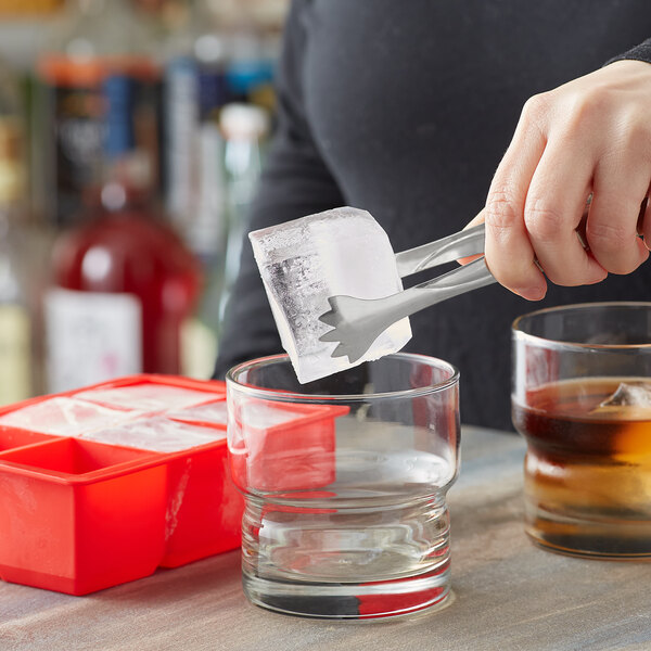 A person using a red Choice silicone ice mold to make small ice cubes.
