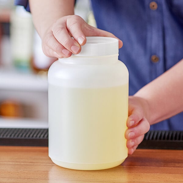 A person holding a Choice plastic container with white liquid and a white lid.