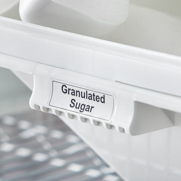 A white Baker's Mark label on a white container filled with granulated sugar.