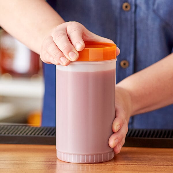 A person holding a Choice plastic container of pink liquid.
