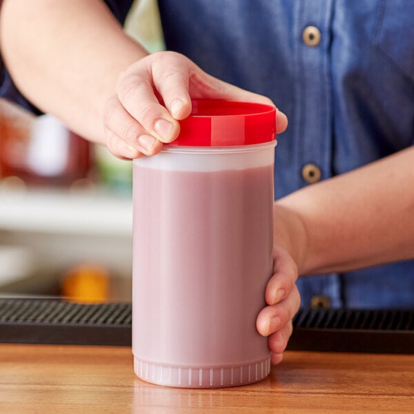 A person holding a Choice plastic container of red liquid.