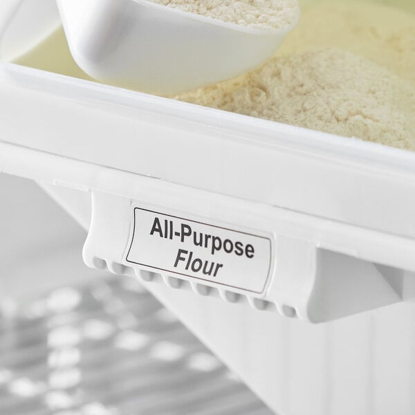 A white Baker's Mark ingredient bin with a white label reading "All Purpose Flour" and a white scoop of flour inside.