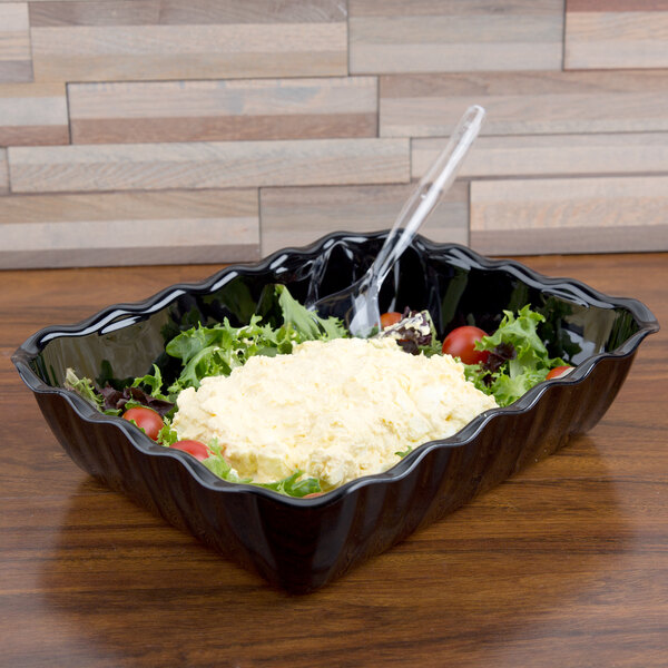 A black Cambro deli crock filled with salad topped with green leaves.