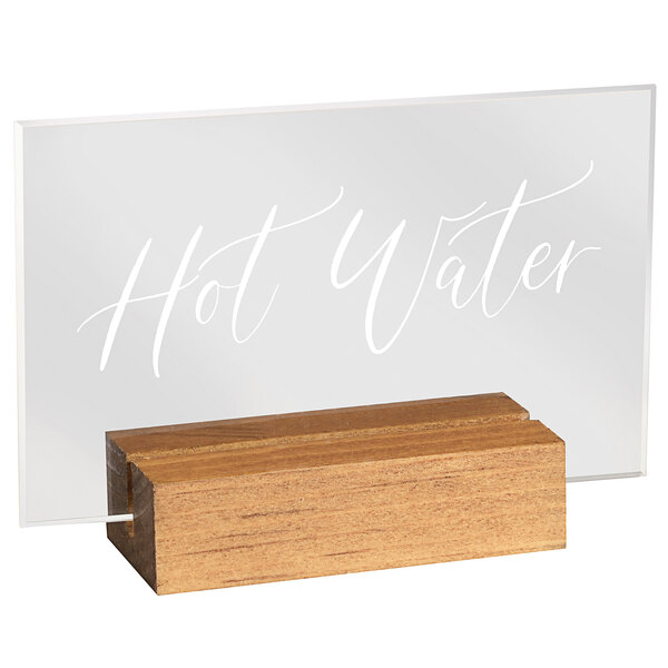 A clear glass sign with "hot water" in wood on a wooden block.