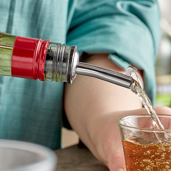 A person using a TableCraft stainless steel liquor pourer to pour liquid into a glass.