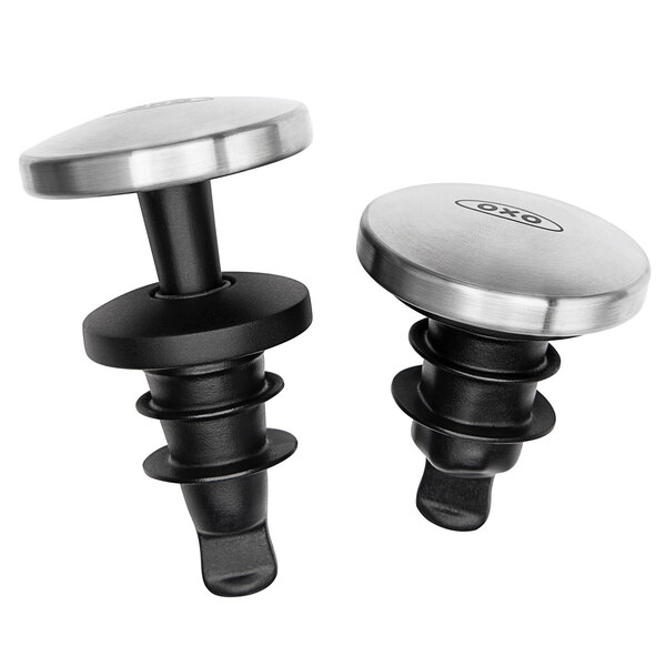 Two black and silver metal OXO wine stoppers on a table.