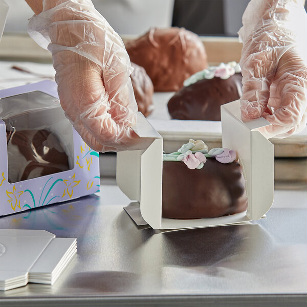 A person in gloves opening a 1 lb. Easter egg box filled with chocolate covered desserts.