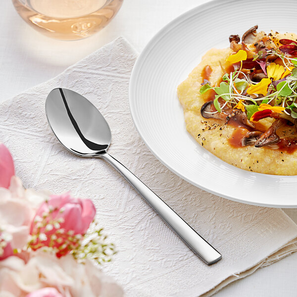 An Acopa stainless steel dinner spoon on a plate of food.