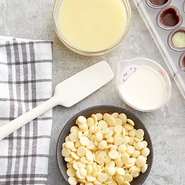A bowl of Callebaut white chocolate chips and a bowl of white liquid.