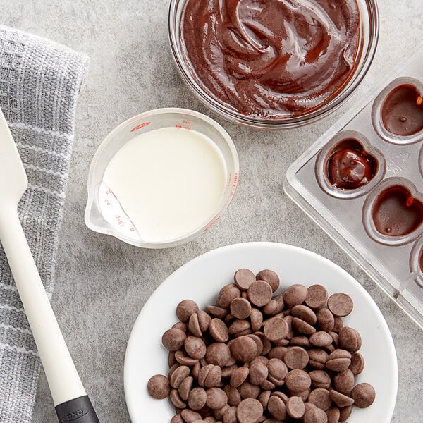 A bowl of Callebaut dark chocolate chips on a table in a professional kitchen.