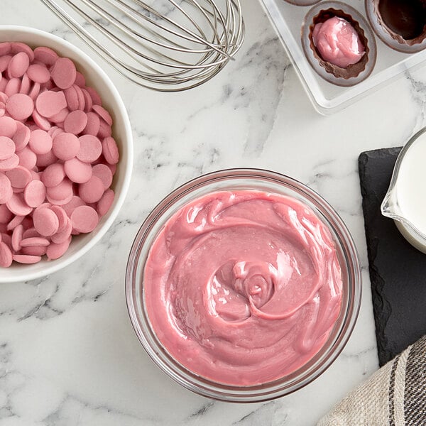A bowl of pink frosting with Callebaut Ruby chocolate chips.
