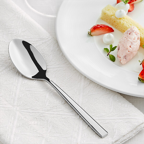 An Acopa stainless steel teaspoon on a white plate with strawberries and cream.