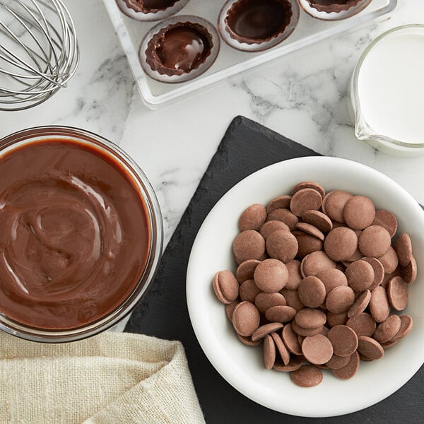 A bowl of Cacao Barry milk chocolate pistoles on a counter.