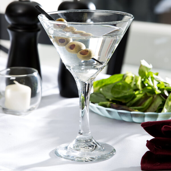 A Libbey martini glass with olives on the rim.