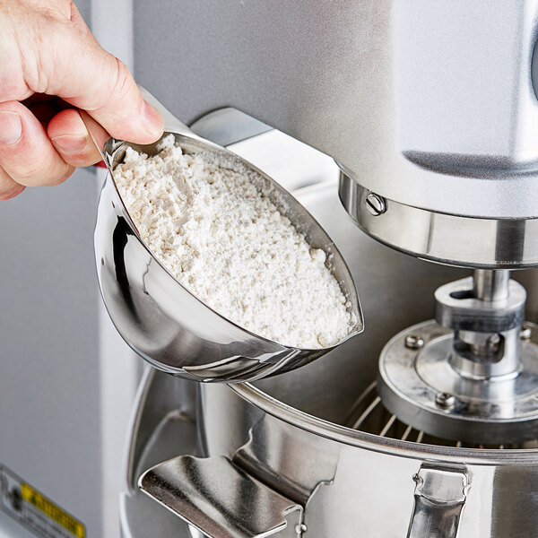 A person using a Vollrath stainless steel transfer bowl to scoop flour.