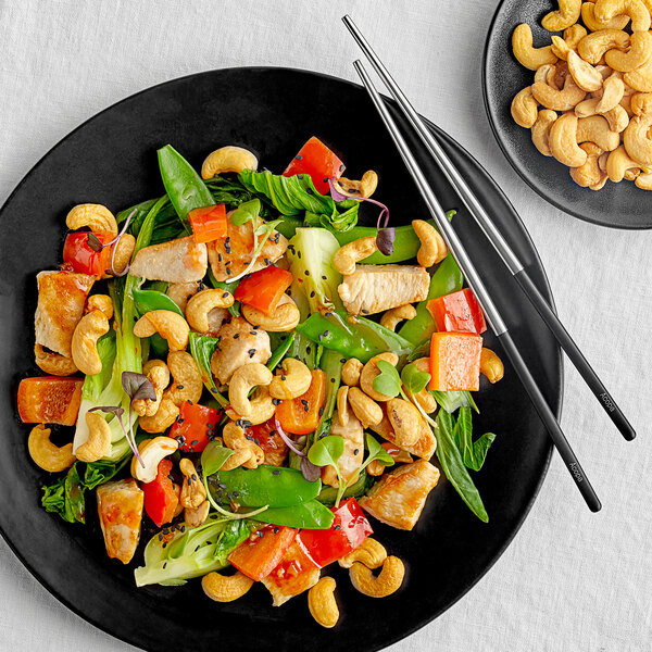 A plate of food with cashews on a table in an Asian cuisine restaurant.
