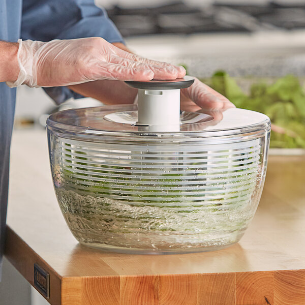 A person cutting lettuce in a OXO salad spinner.